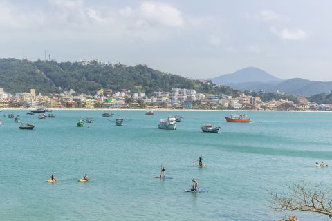 Baía de Bombinhas com mar turquesa, barcos ancorados e casario colorido ao fundo